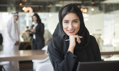 Smiling Arab businesswoman holding pen in office