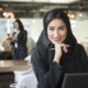 Smiling Arab businesswoman holding pen in office